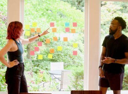 a woman pointing to sticky notes arranged on a window